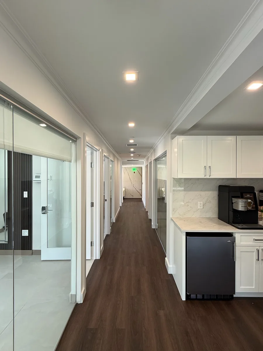 Long office corridor lit by a row of recessed ceiling lights